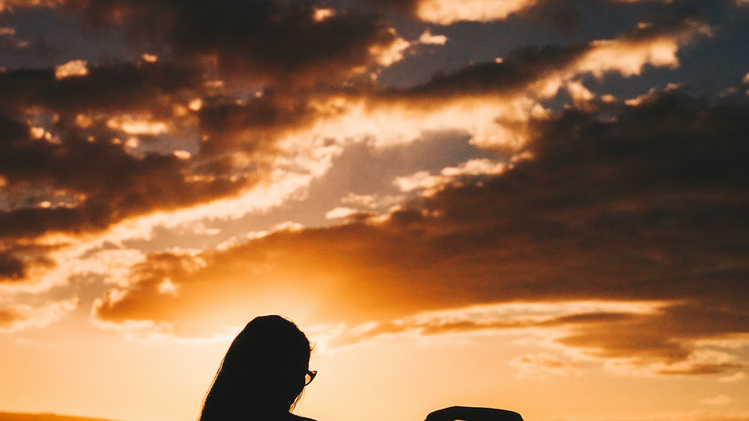 Silhouette of mother and child against a golden-hour sky. Photo by Guille Pozzi on Unsplash.