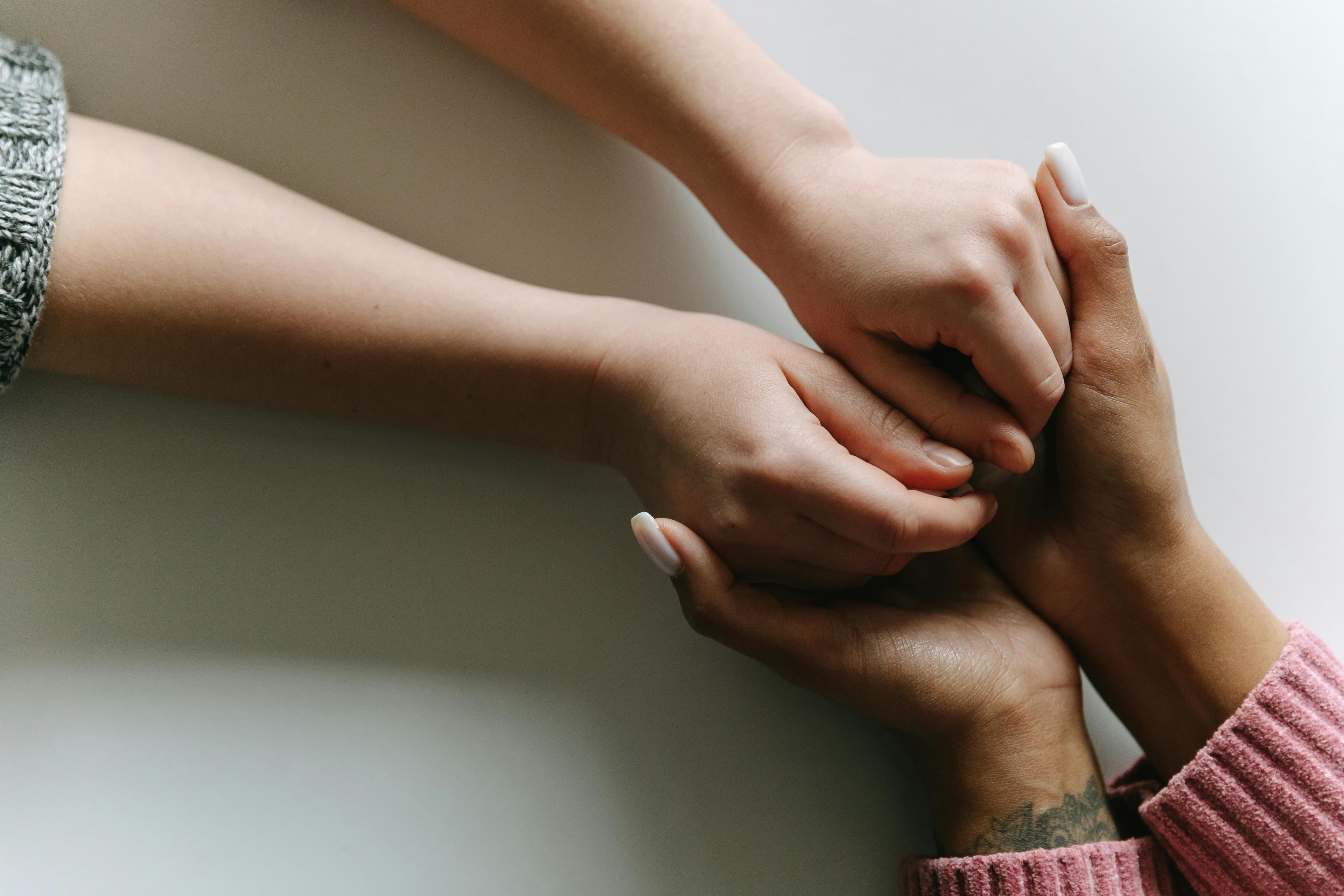 Two hands meeting — the relational ground of the work.